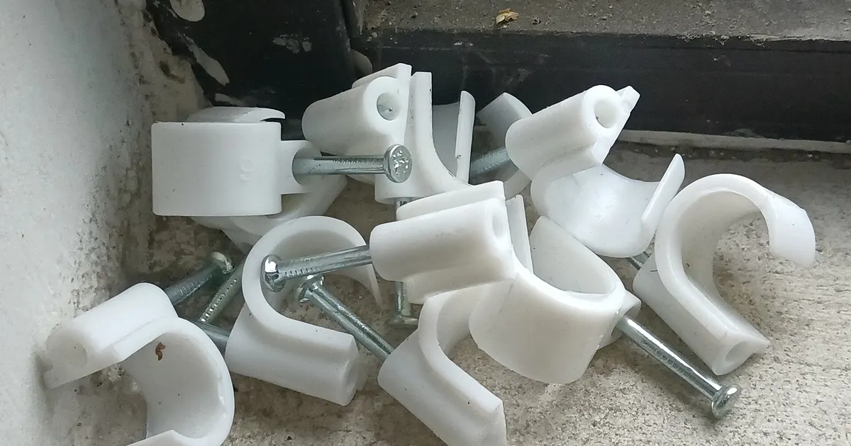 White plastic cable clips with screws, small parts that grip by elastic deflection like an acetal snap fit