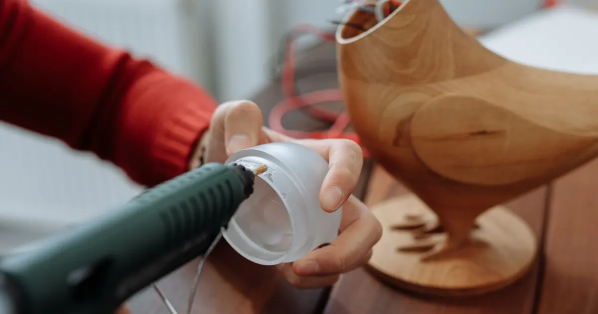 Hand applying hot-melt glue to a small plastic part, a joining method that suits bonding Delrin poorly